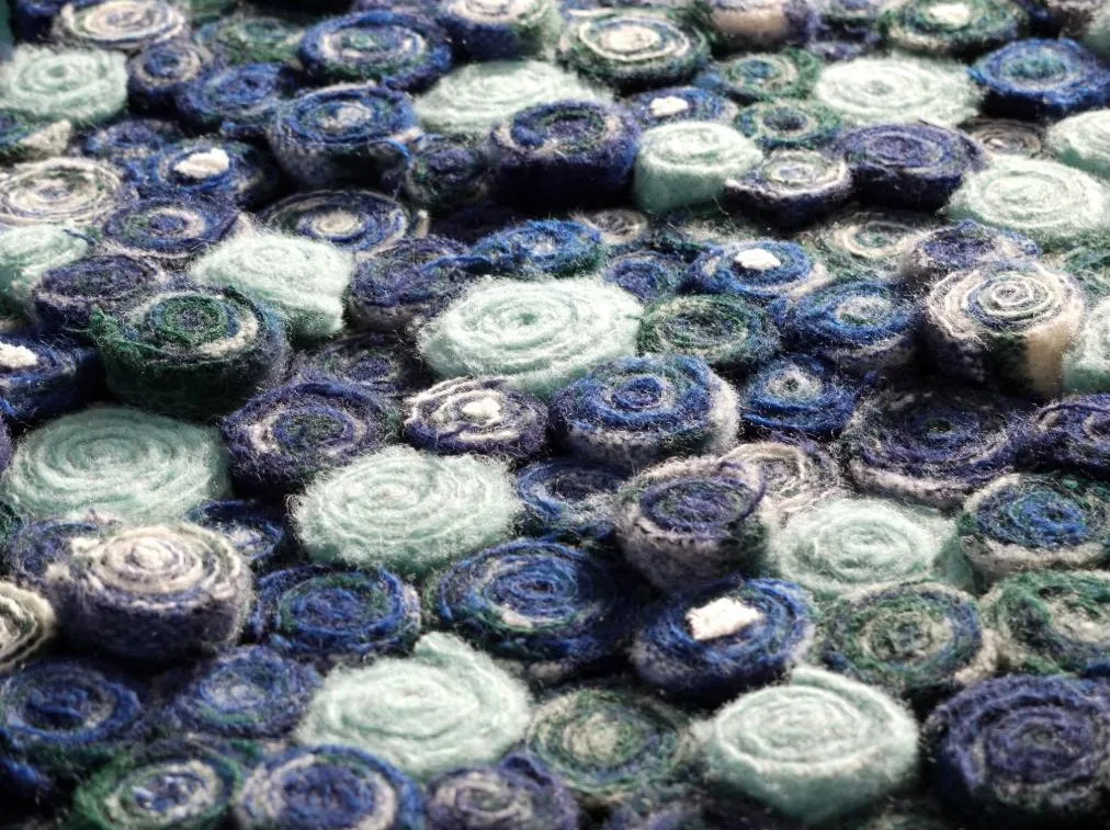 Vloerkleed van opgerolde repen oude wollen dekens in blauw- en groentinten