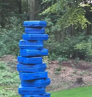 Toren van blauw geschilderde gestapelde koffers in het bos